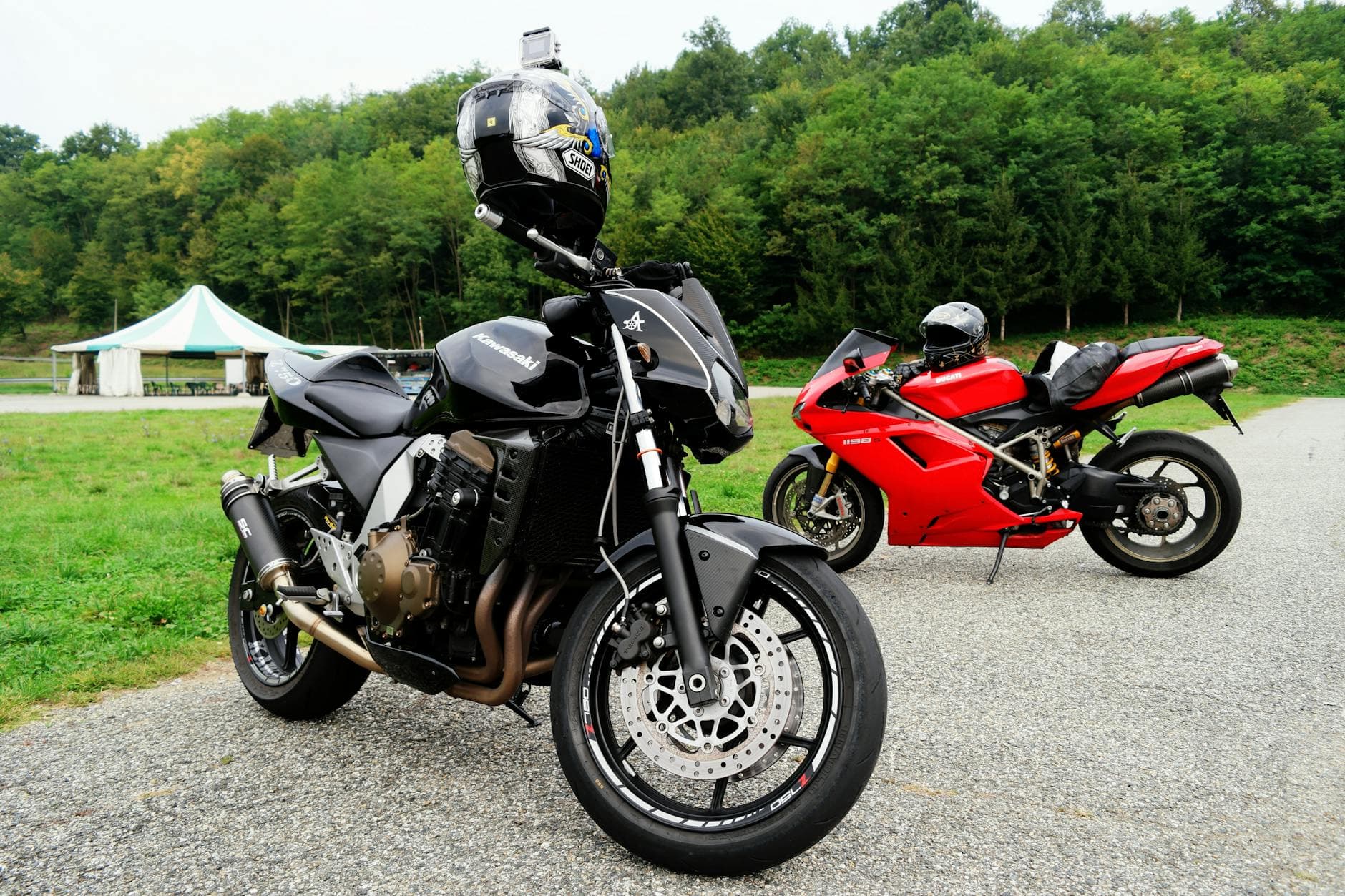 Two sport motorcycles parked on a pavement in a scenic countryside with lush green forest.